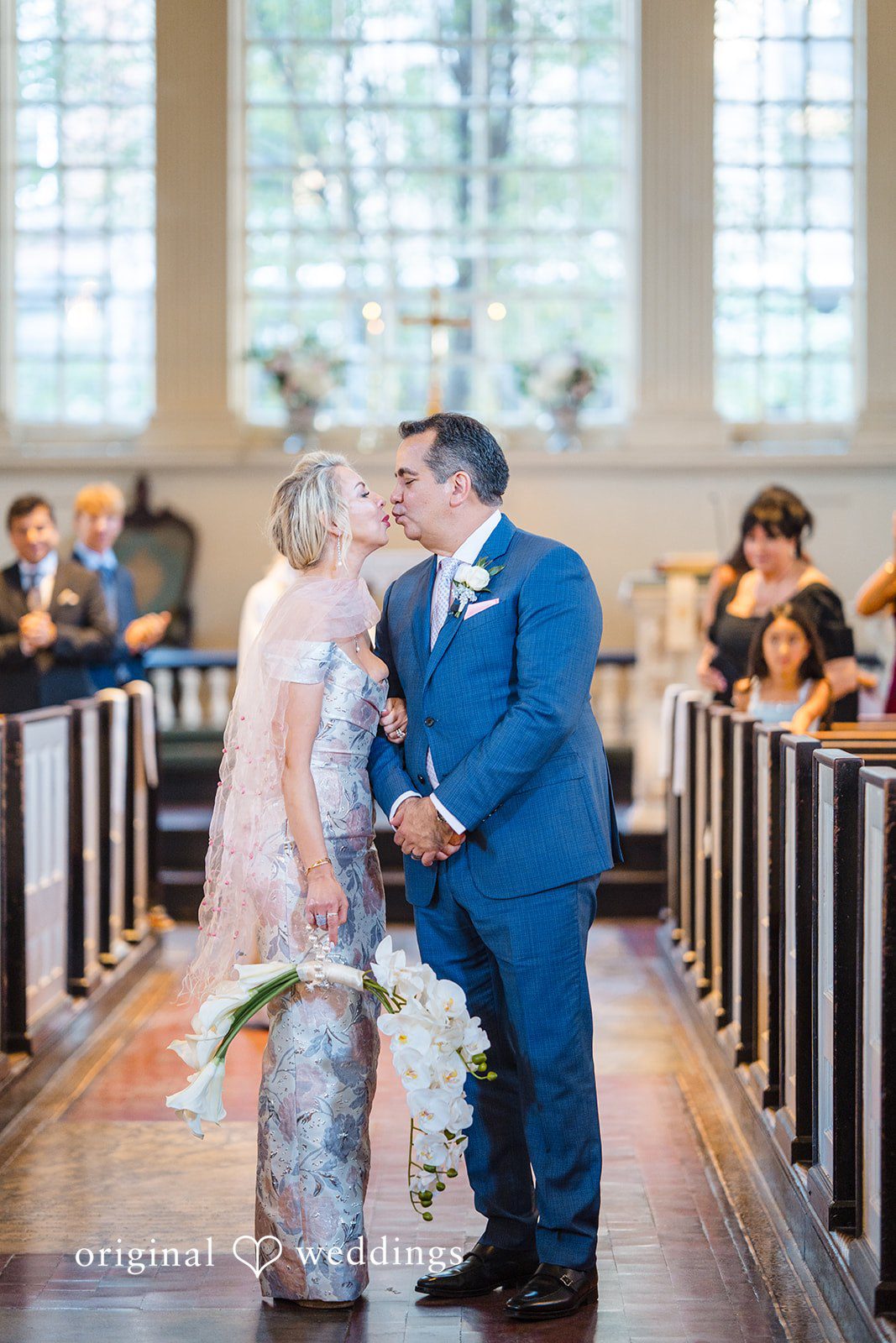 Alexandra + John Couple sharing a kiss in the church aisle