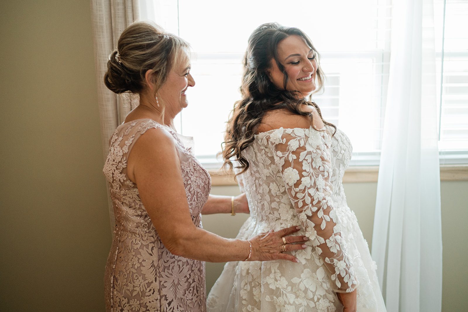 Mother helping the bride into her lace gown