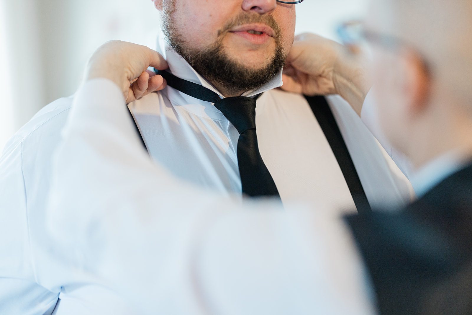 Groom getting help with his tie