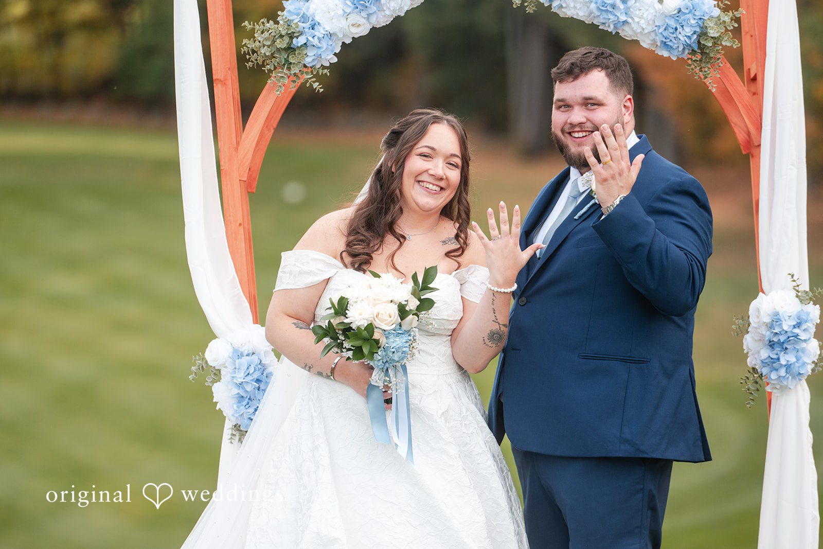 Erika and Daniel smiling at the ceremony arch, captured by Boston wedding photographers from Original Weddings at Berlin Country Club
