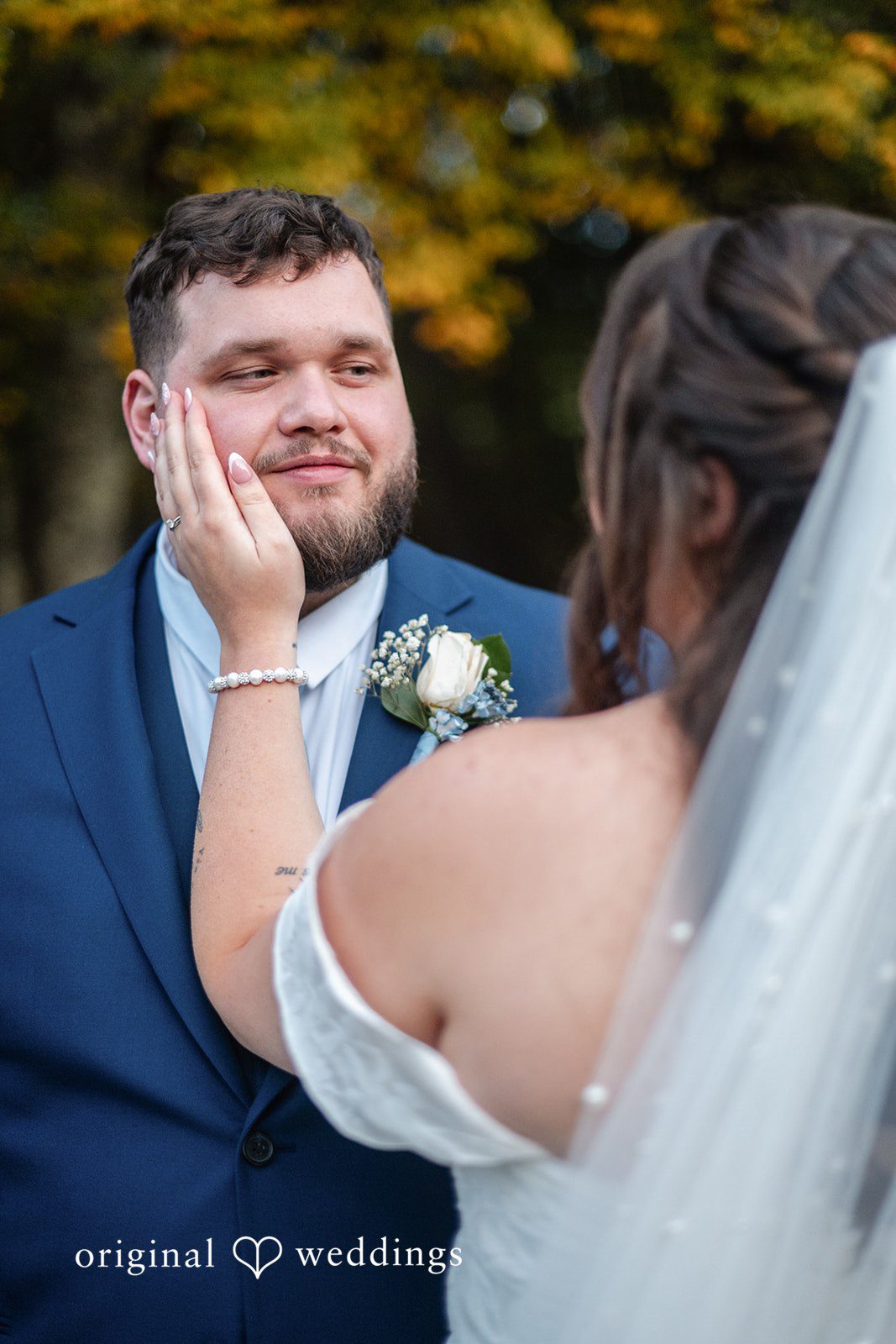 Groom smiling as the bride holds his face