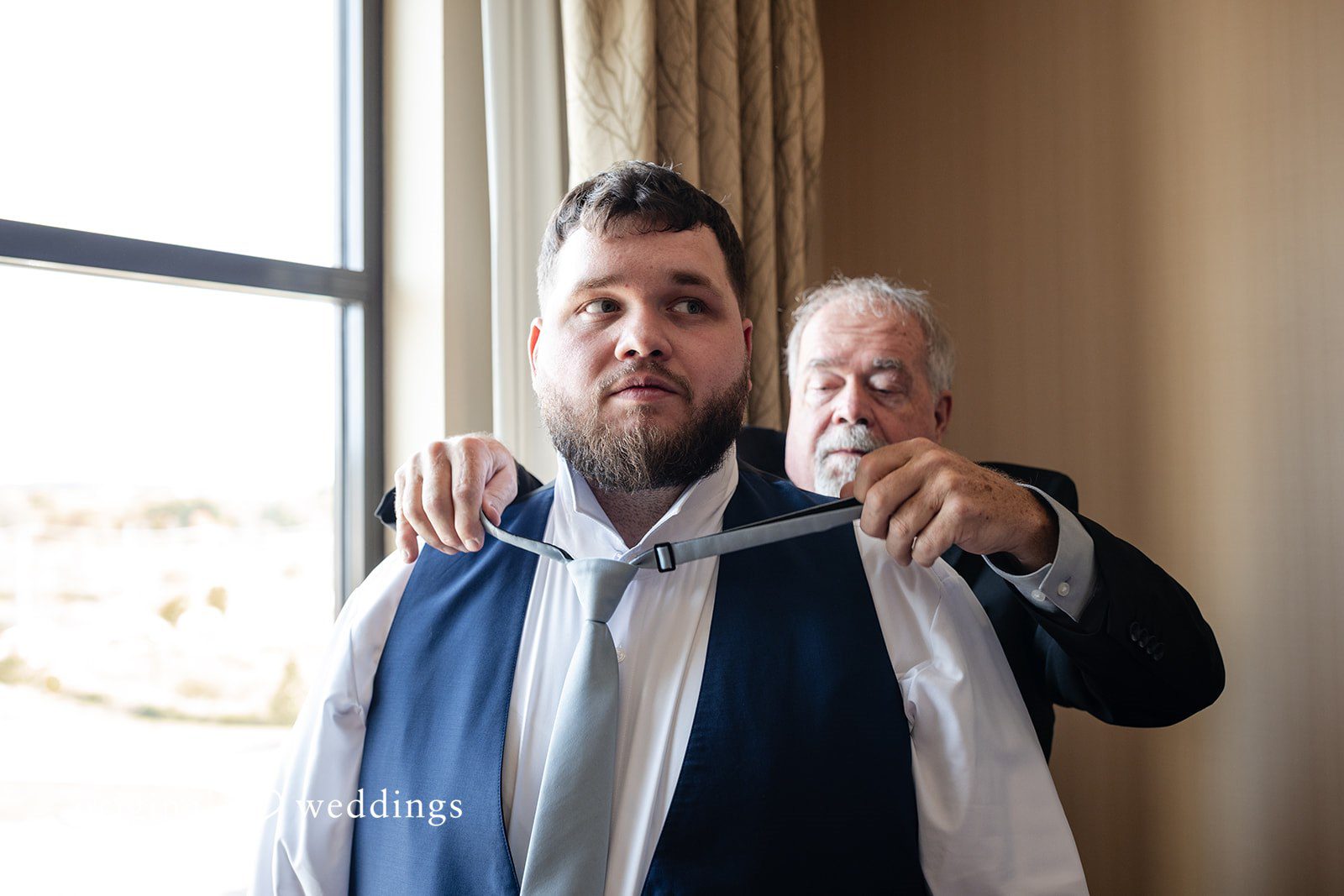 Groom getting ready with help from a friend