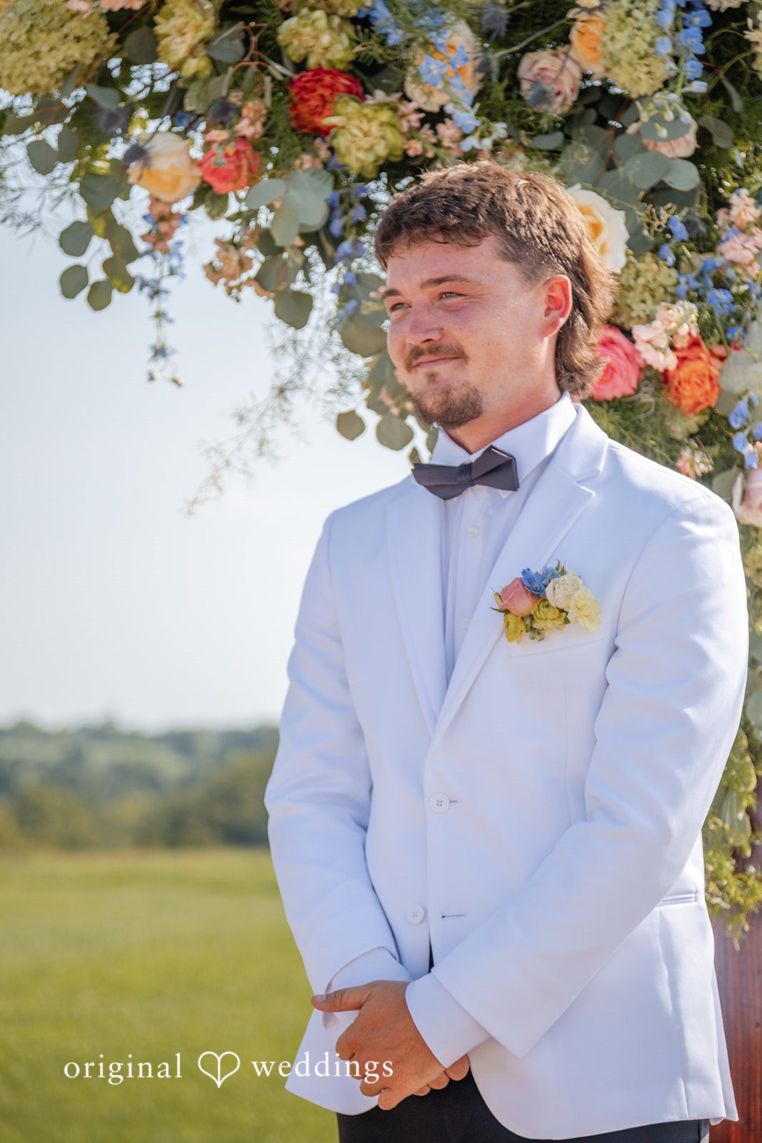 Groom smiling in his white jacket at Bryton Barn