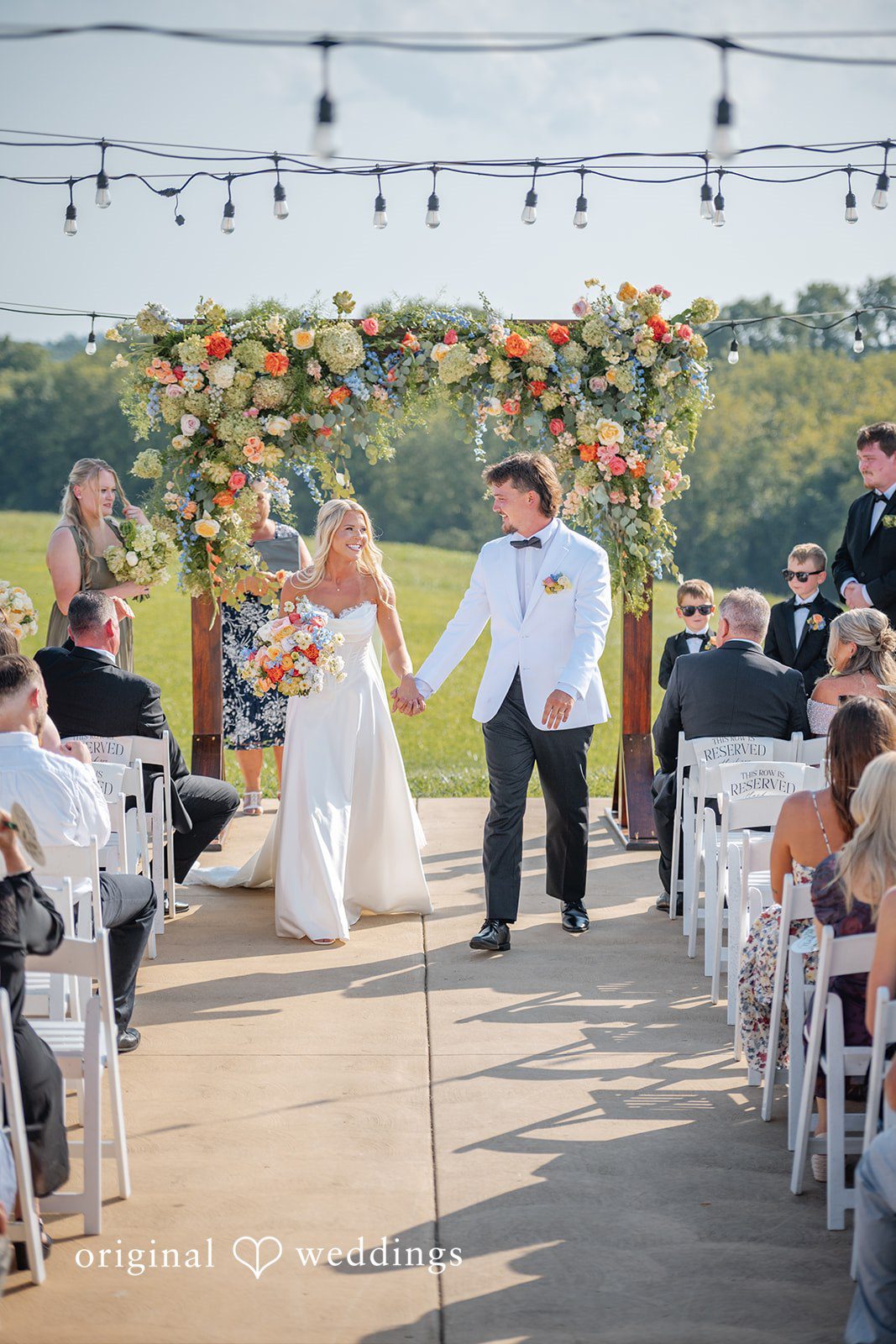Bride walking toward the floral arch