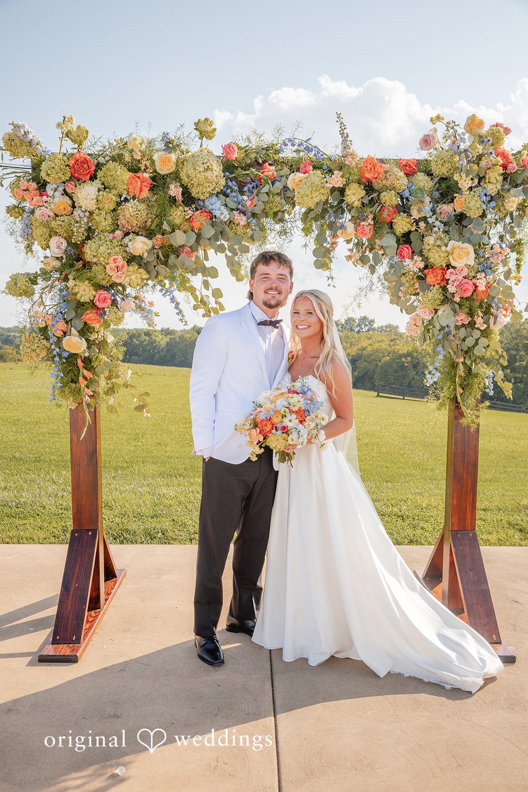 Couple standing under the floral arch at Bryton Barn
