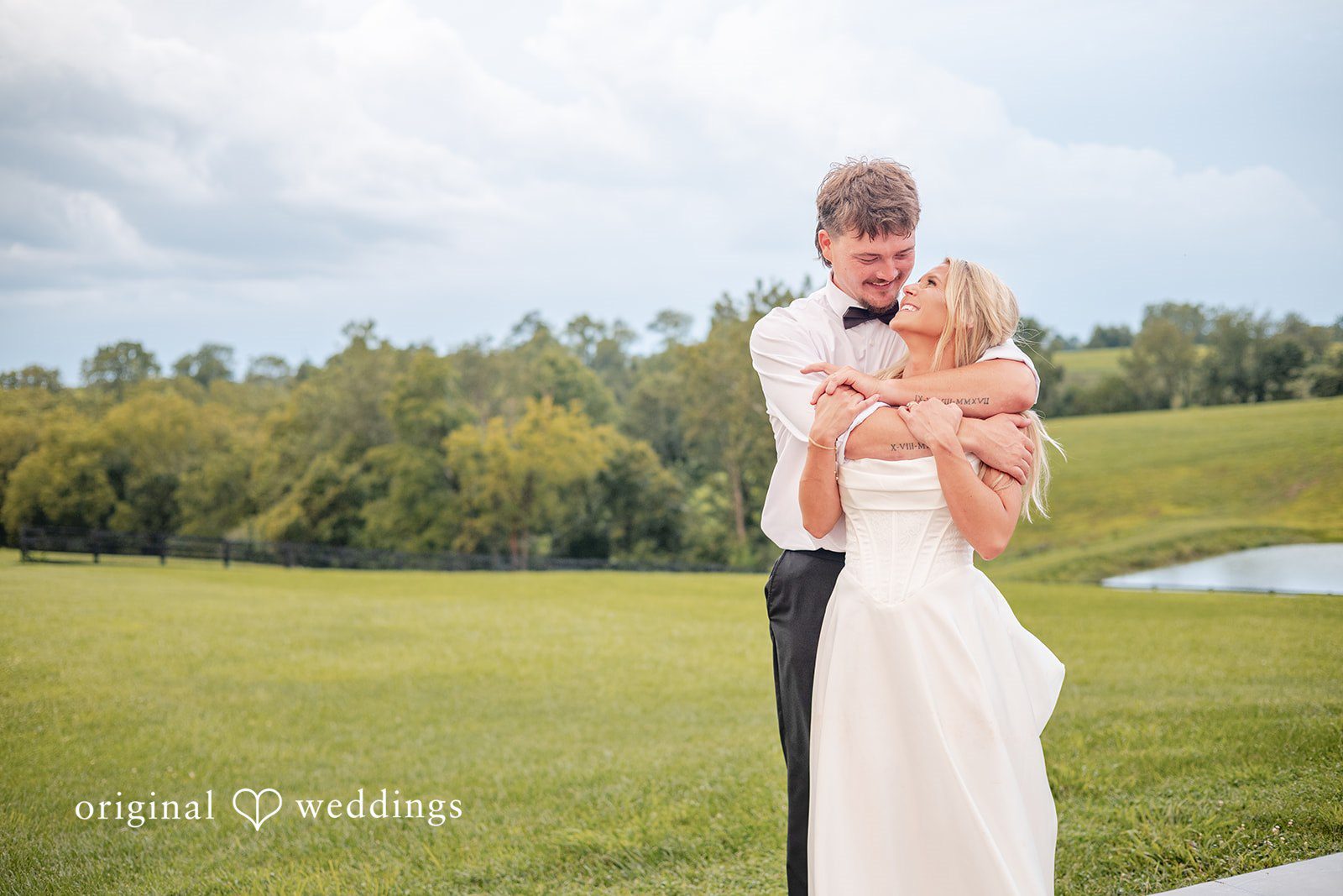 Groom hugging the bride in the green field at Bryton Barn