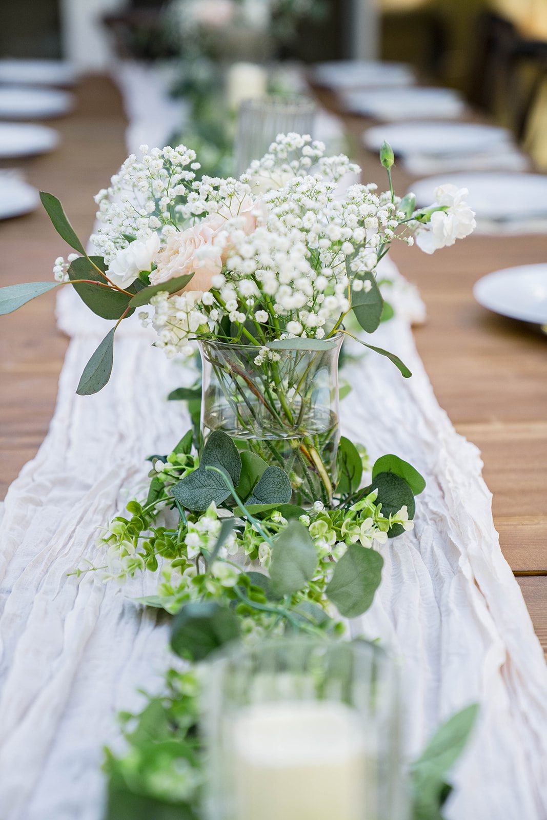 Reception table with greenery and white blooms at a California backyard wedding