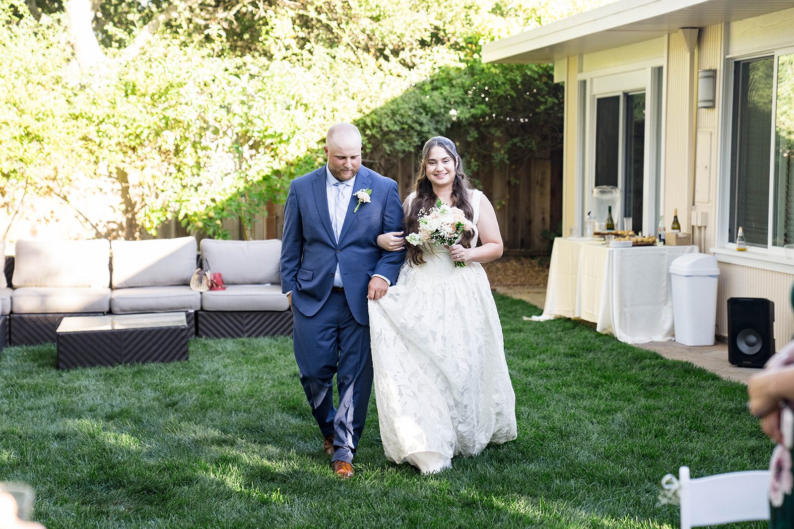 Bride and groom walking together across the backyard lawn, captured by San Francisco wedding photographers from Original Weddings at a California backyard wedding