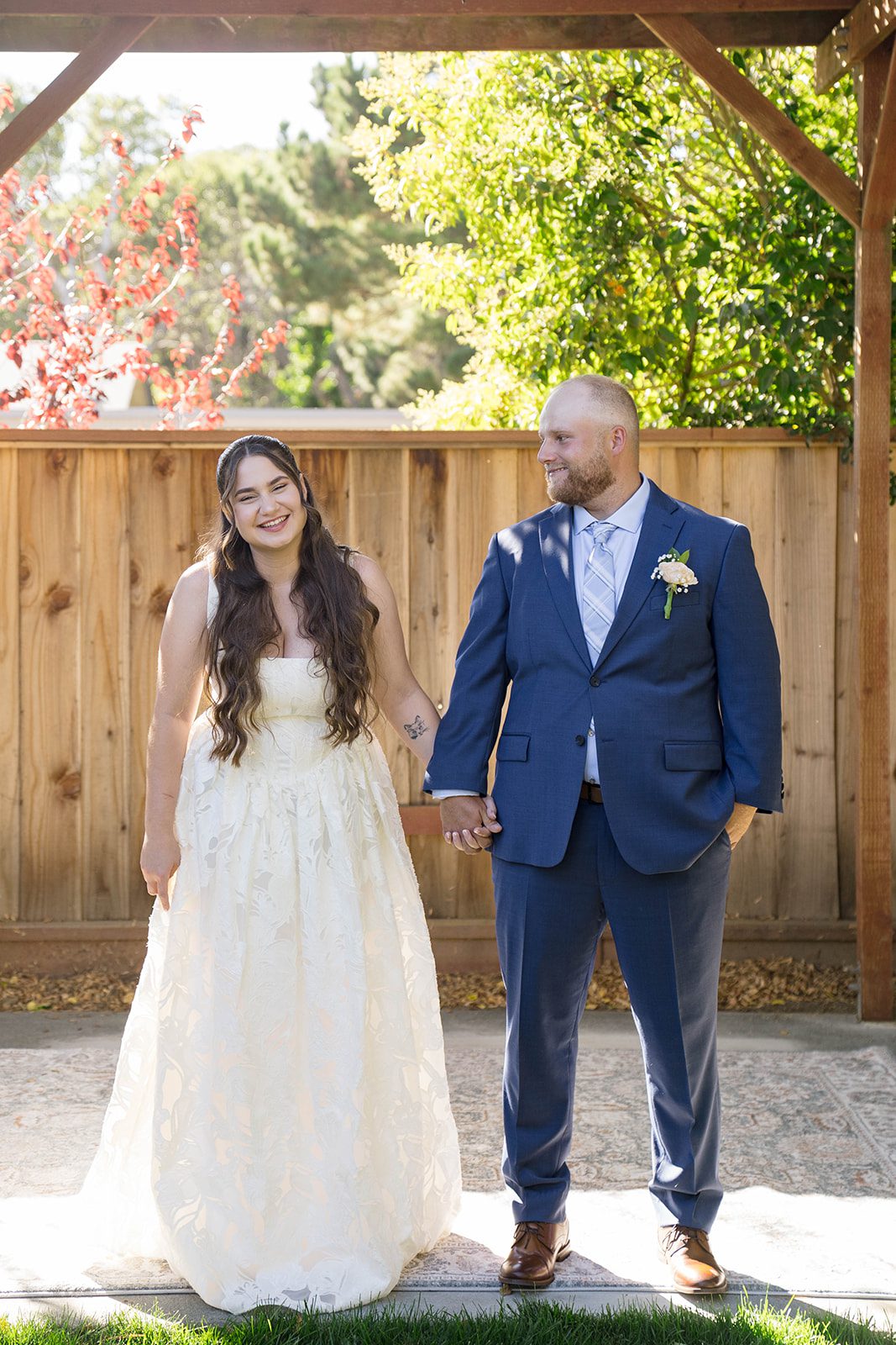Couple standing by the wooden fence at a California backyard wedding