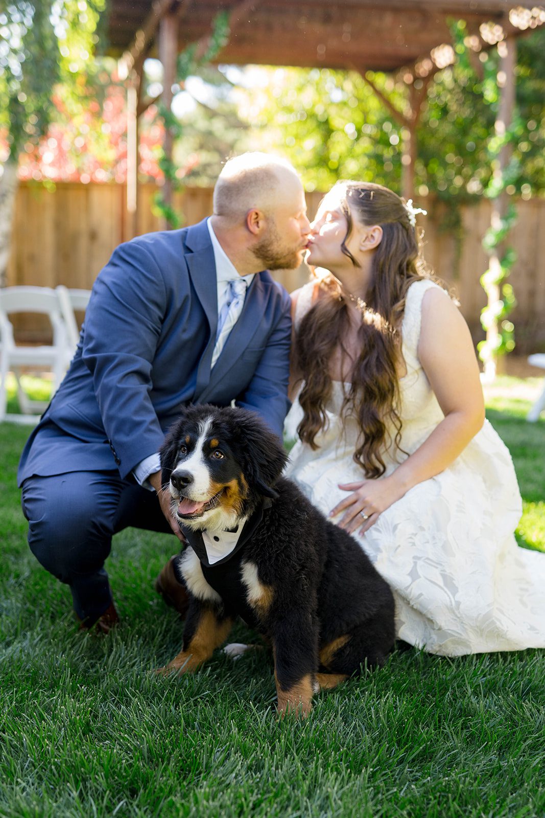 Couple posing with their Bernese puppy at a California backyard wedding