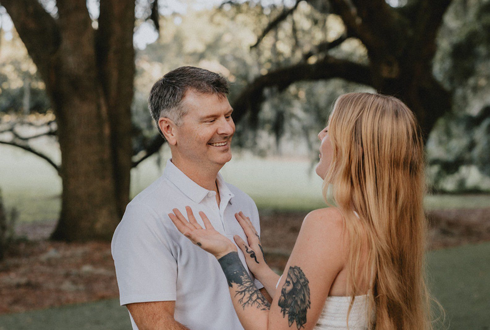 Couple embracing under the live oaks, captured with engagement photography services from Original Weddings at Legare Waring House