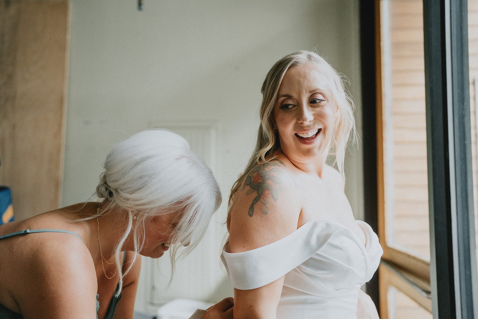 Bride laughing with a friend while getting ready