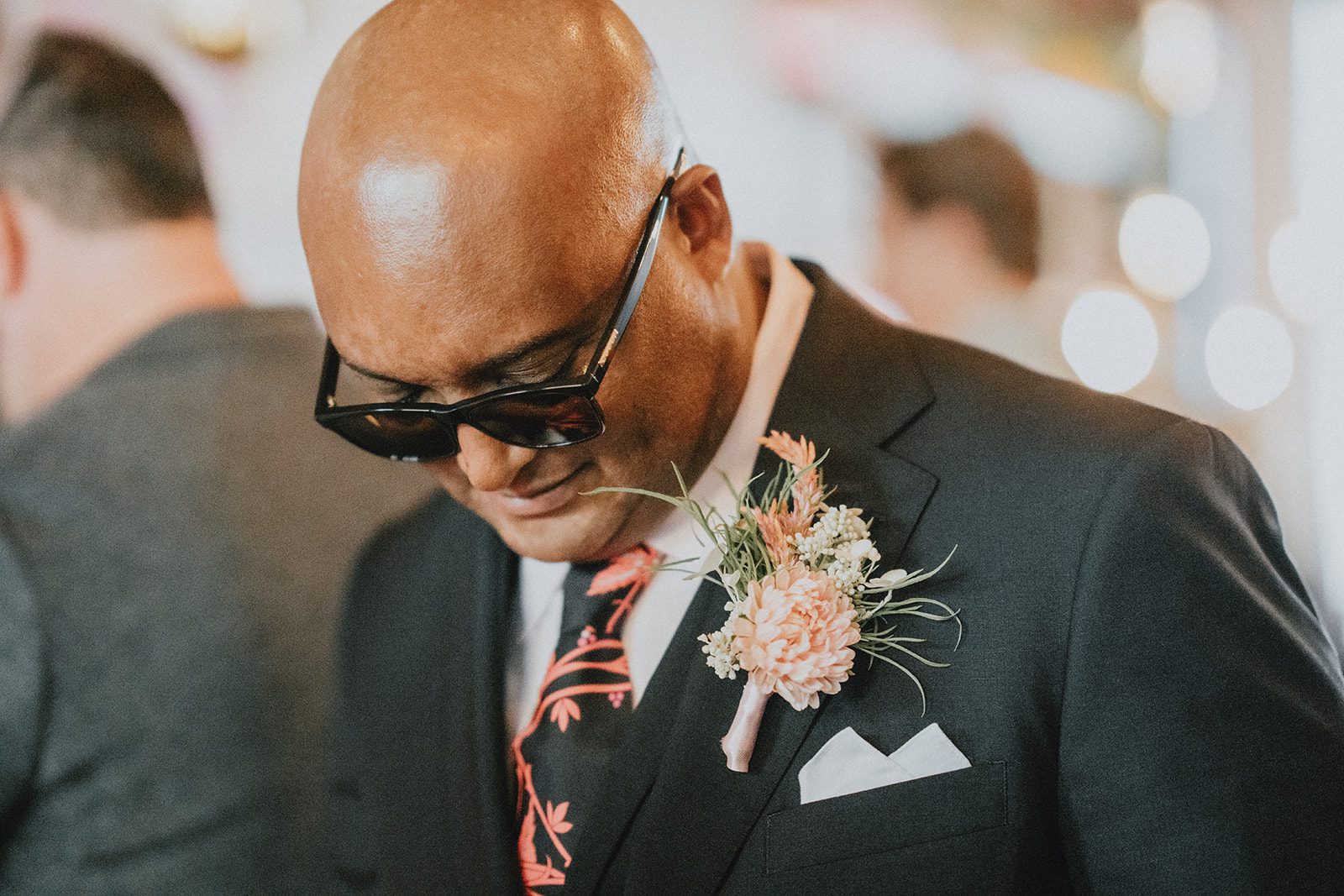 Groom smiling as he adjusts his boutonniere