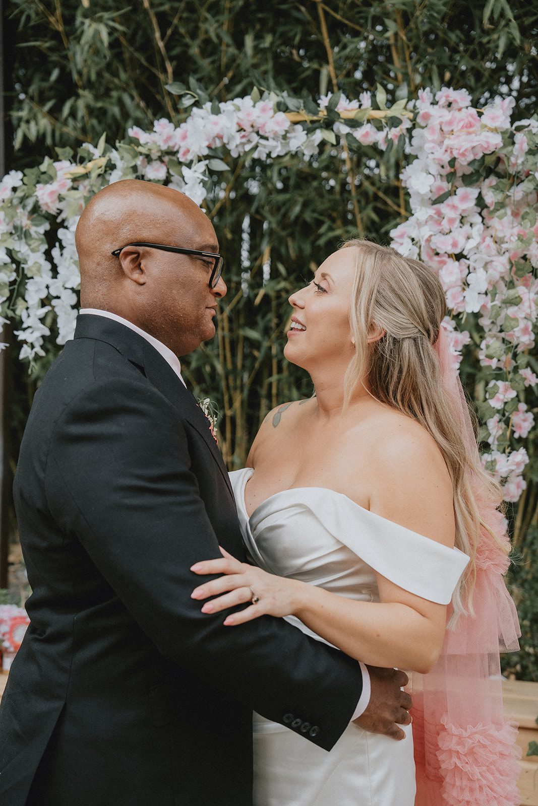 Bride and groom hugging by the floral arch
