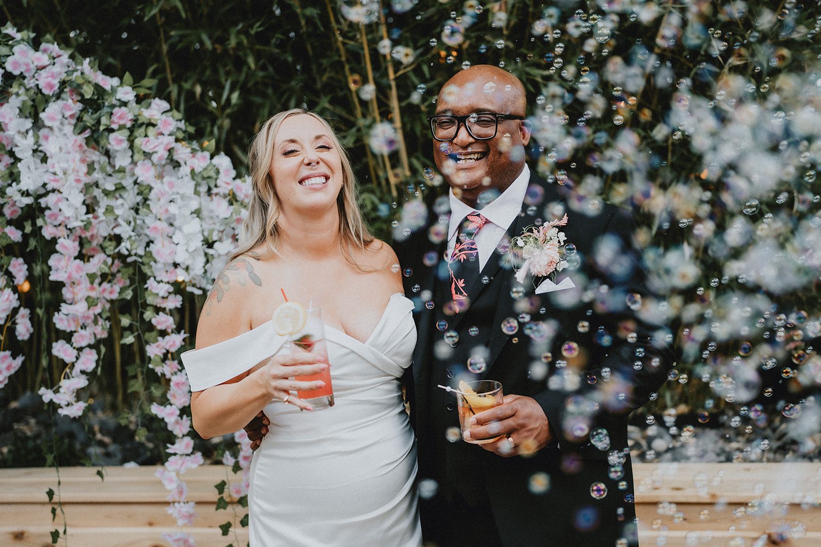 Bride and groom smiling under the floral arch, captured by Portland wedding photographers from Original Weddings at Chill Chill Chill