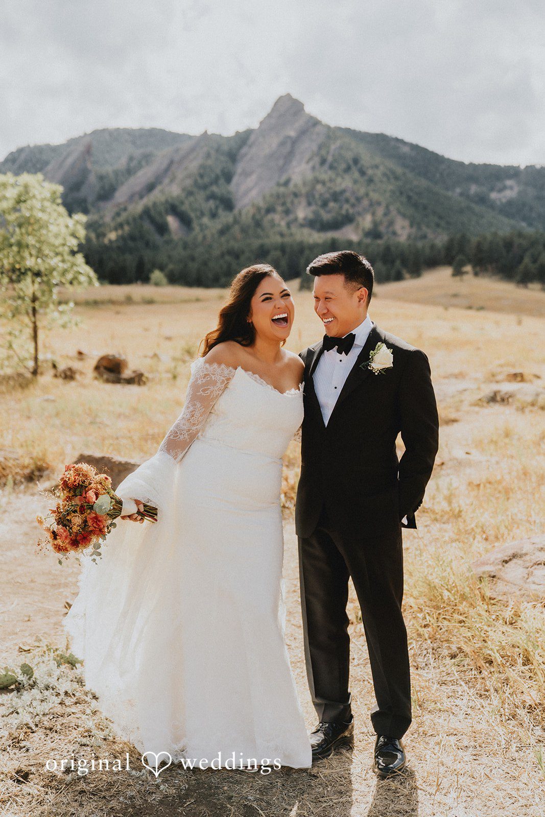 Sonia + Michael Bride and groom laughing together near Church Ranch Event Center with mountains behind