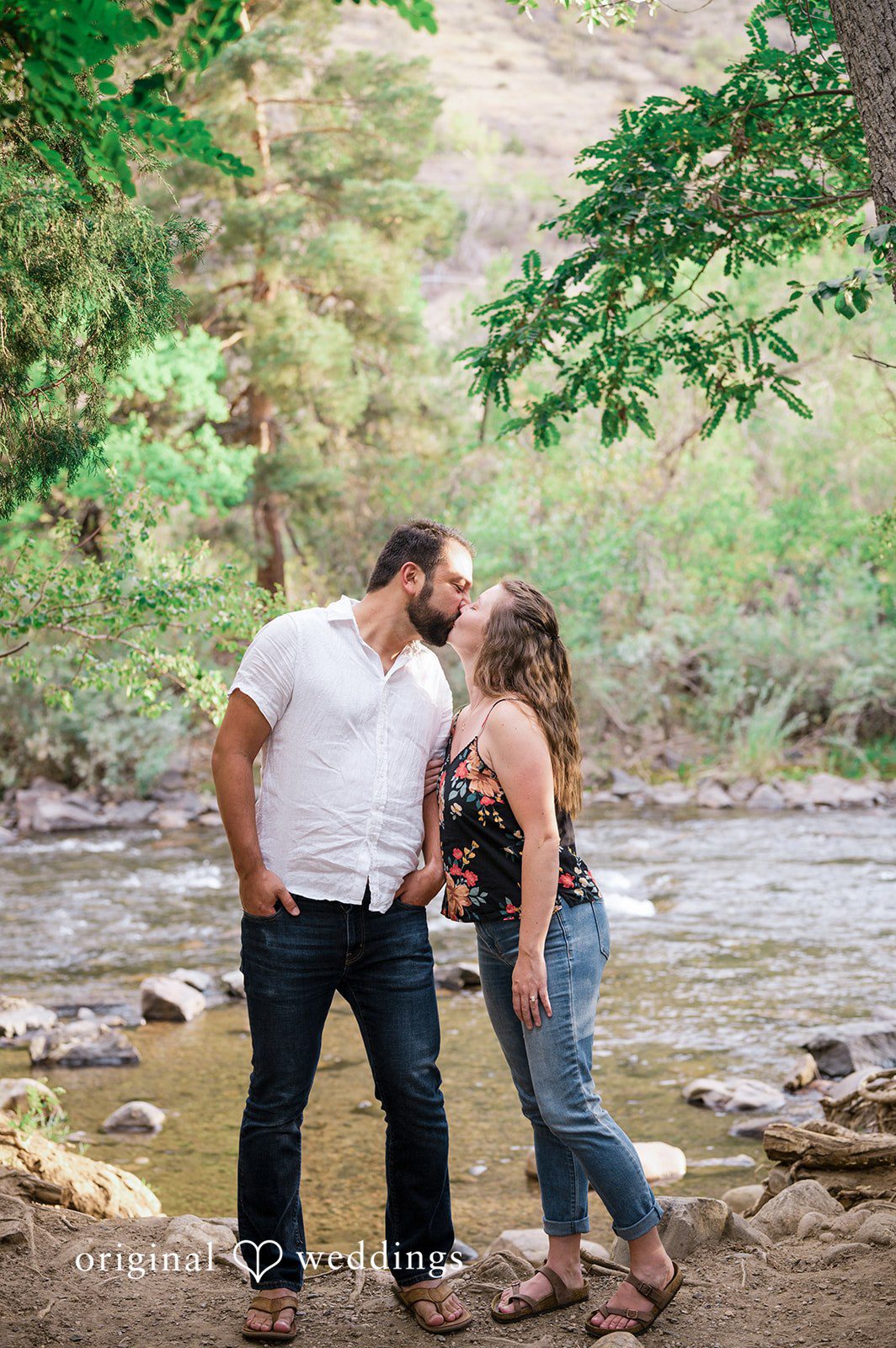 Theodore + Kathryn Couple hugging near a rocky stream at Clear Creek Trail.