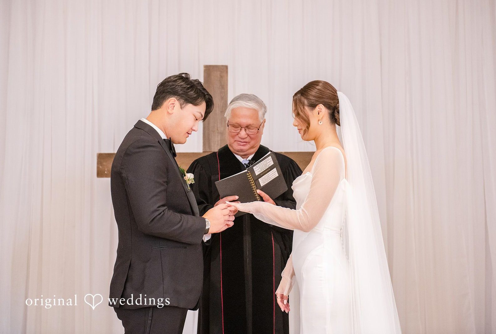 Bride and groom exchanging rings with their officiant, captured by Atlanta wedding photographers from Original Weddings at Collier Hall