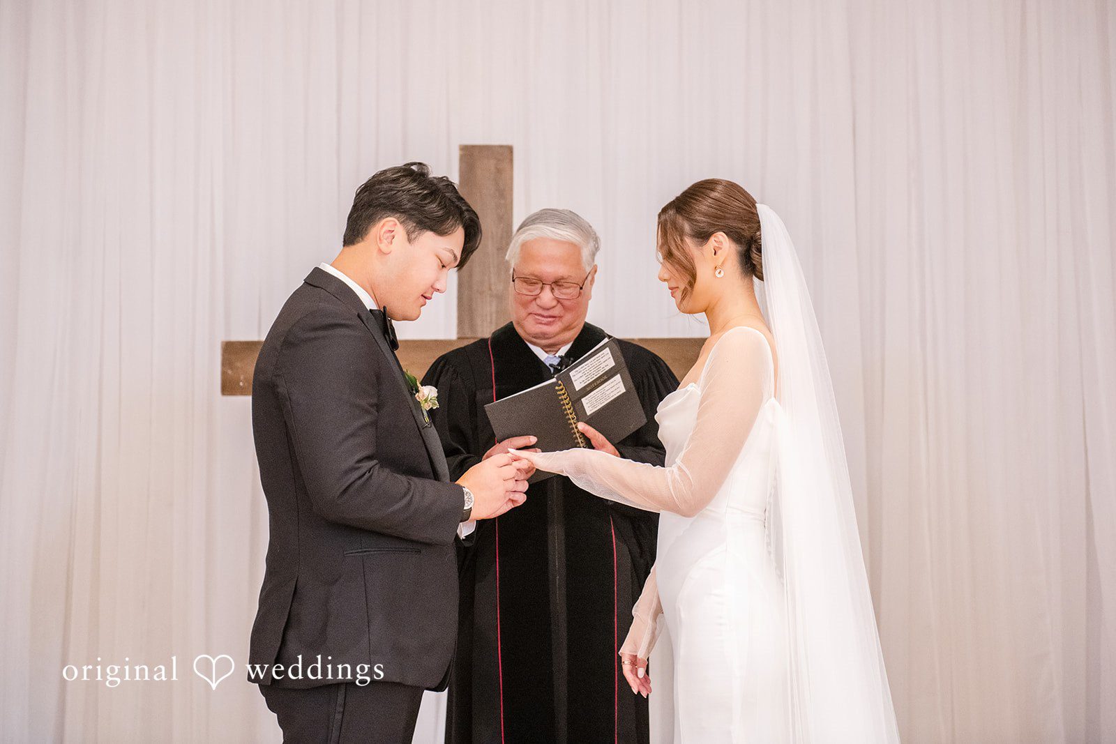 Yuri + Zachary Bride and groom exchanging rings with their officiant, captured by Atlanta wedding photographers from Original Weddings at Collier Hall