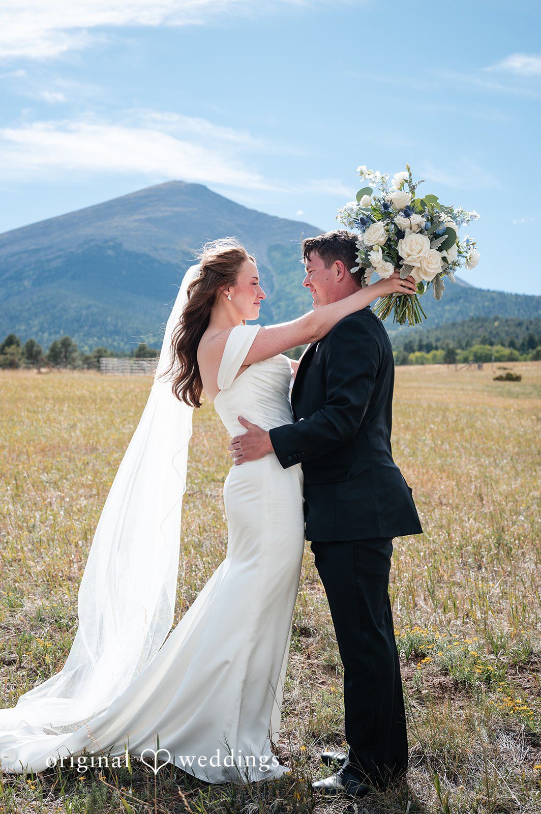 Erin + John Erin and John with the mountains behind them, captured by Denver wedding photographers from Original Weddings