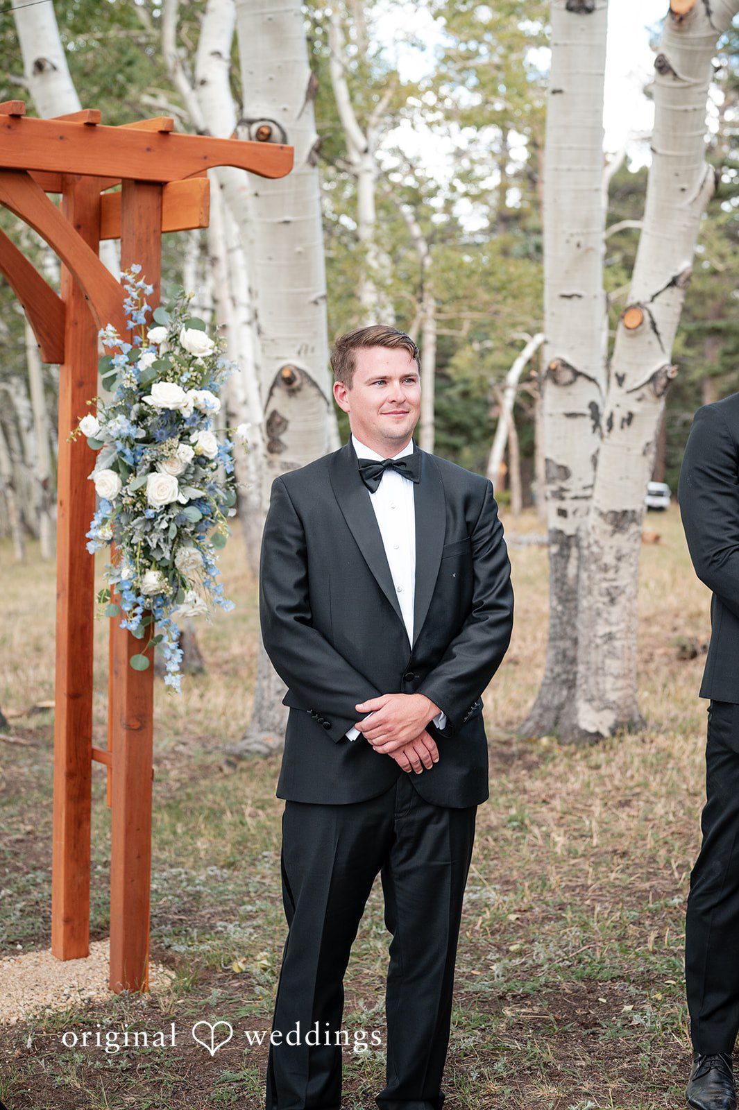 Erin + John Groom waiting by the wooden arch at the Colorado backyard wedding