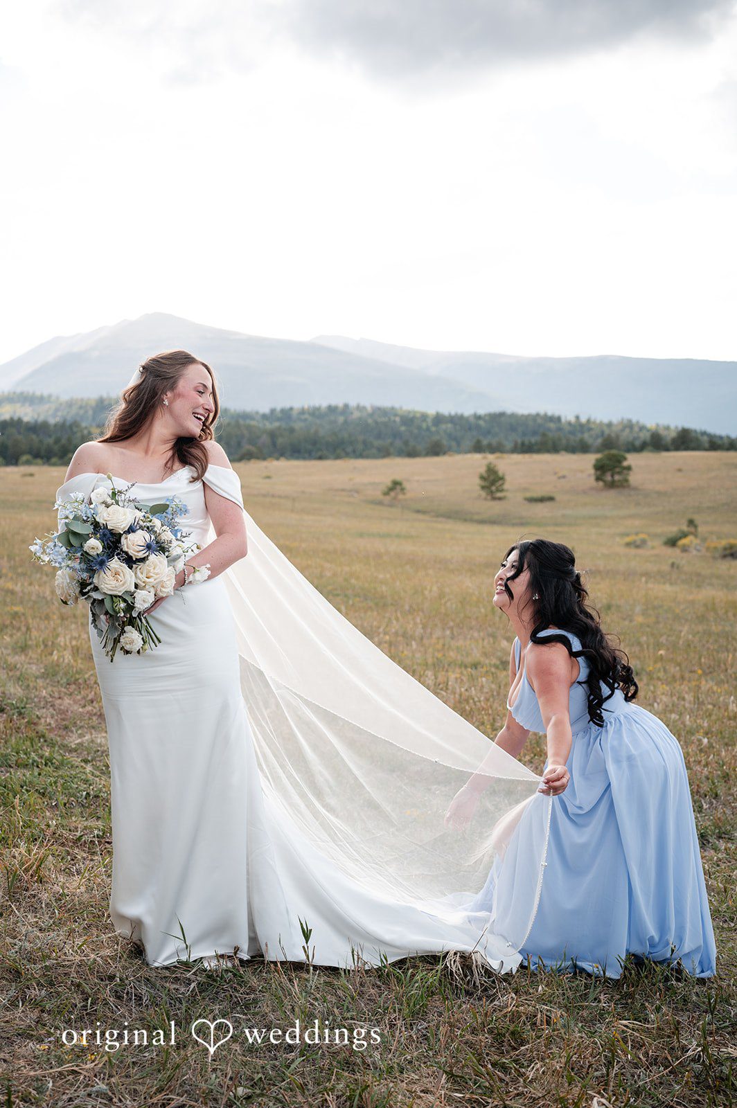 Erin + John Bridesmaid fluffing the bride's dress in the meadow