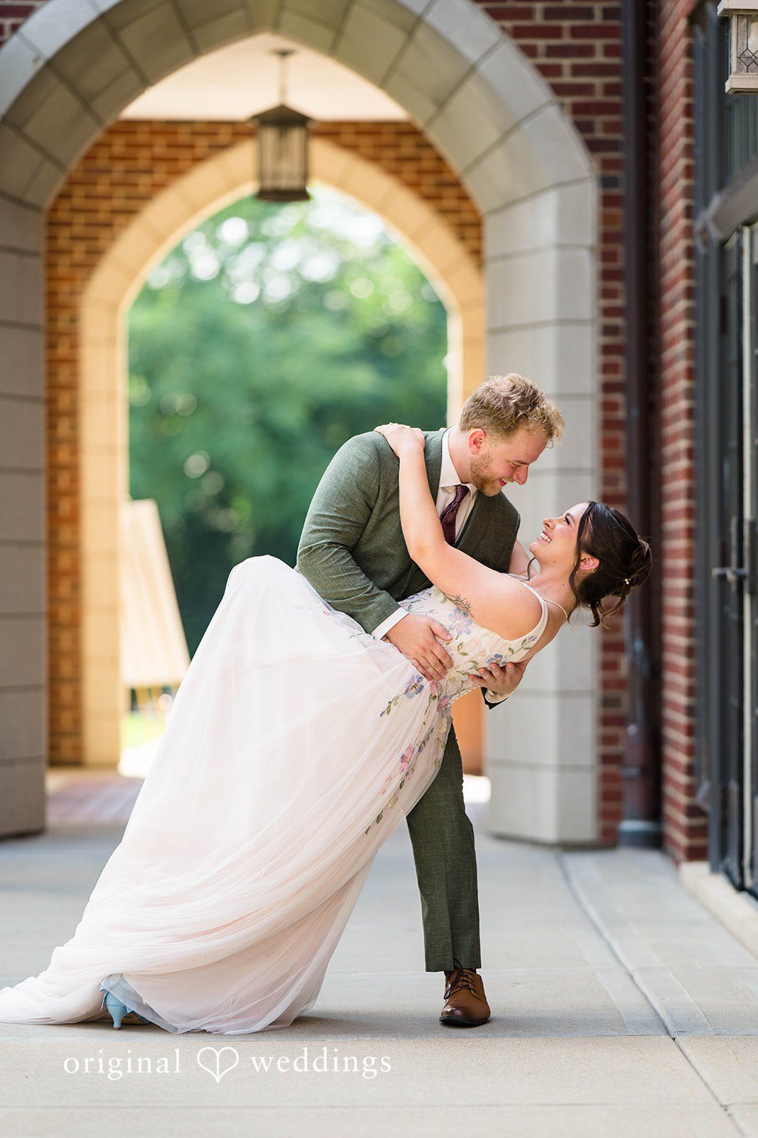 Griffin + Lauren Couple sharing a dip kiss in a stone archway at Community House Winnetka