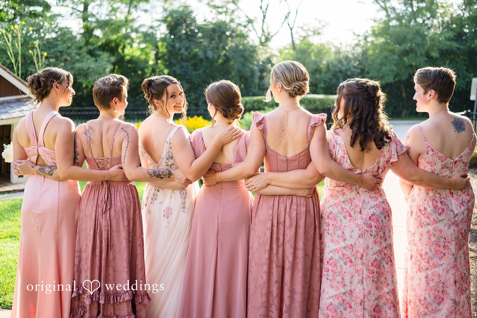 Griffin + Lauren Bridesmaids in pink dresses with arms around each other