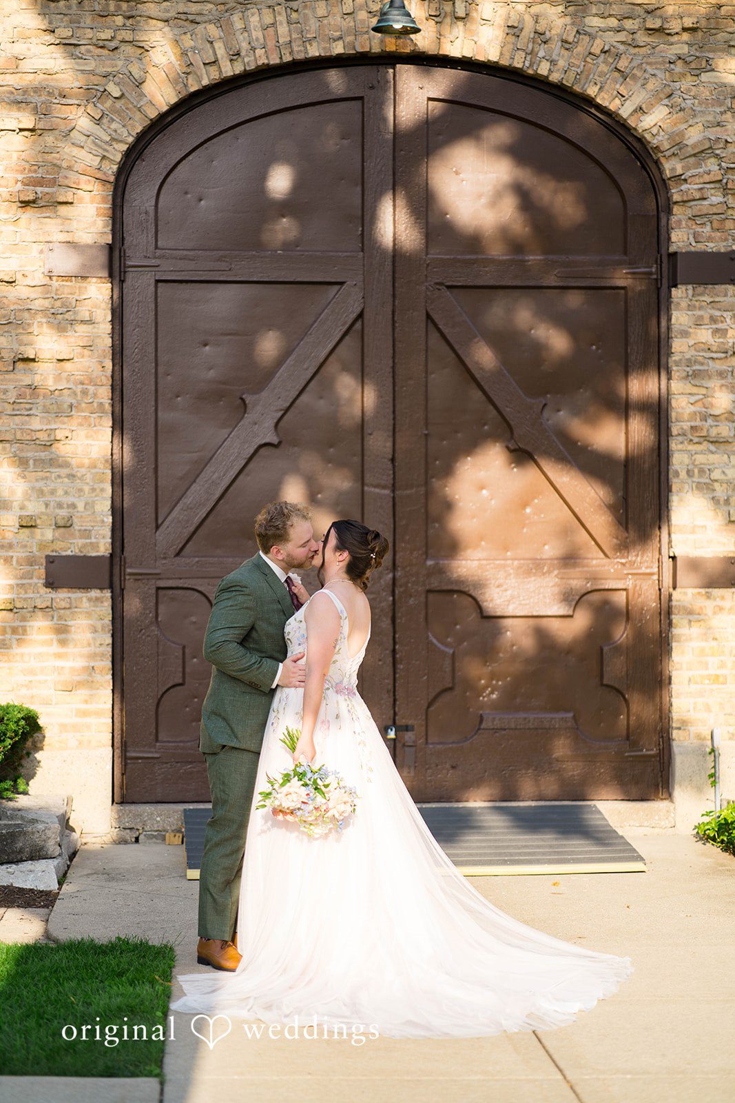 Griffin + Lauren Bride posing by a wooden door