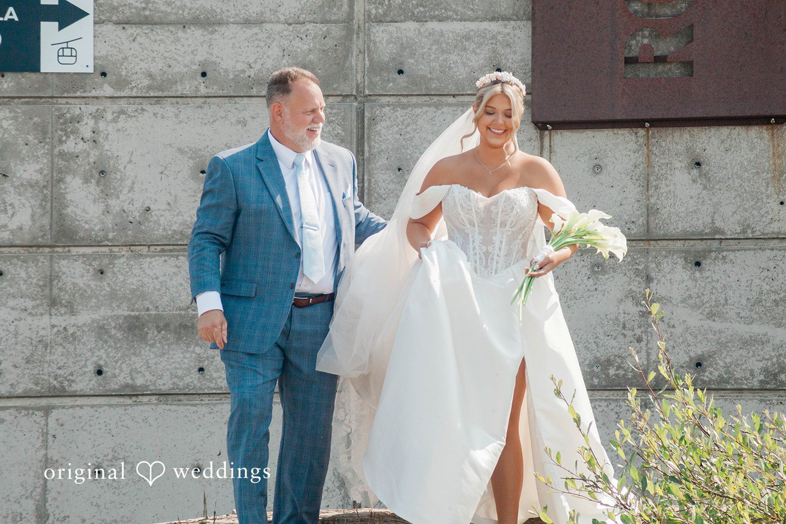 Bethany + Ryan A bride and man walk together along an outdoor path next to a stone wall.