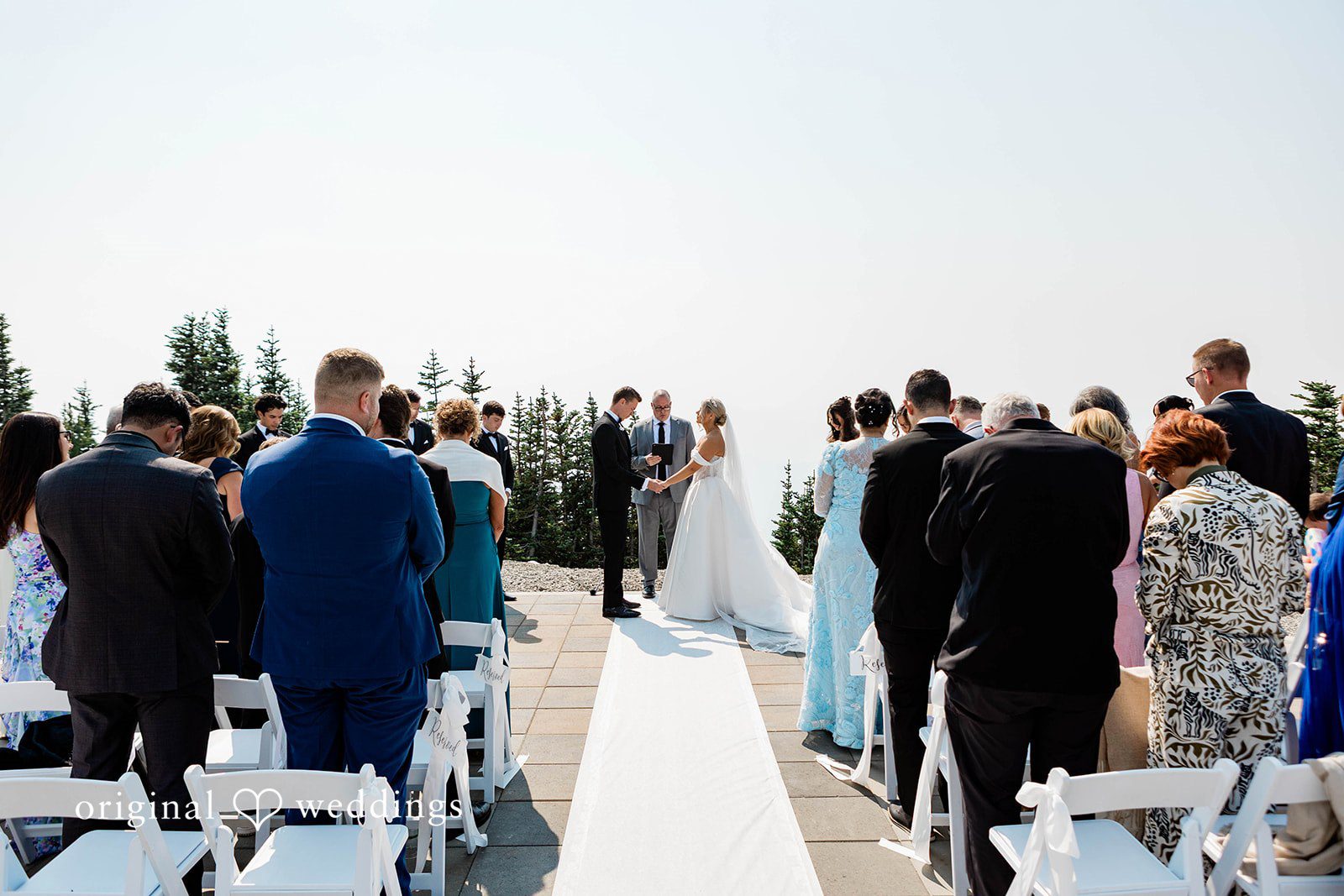 Bethany + Ryan A wide view of an outdoor wedding aisle set up on a high mountain terrace.
