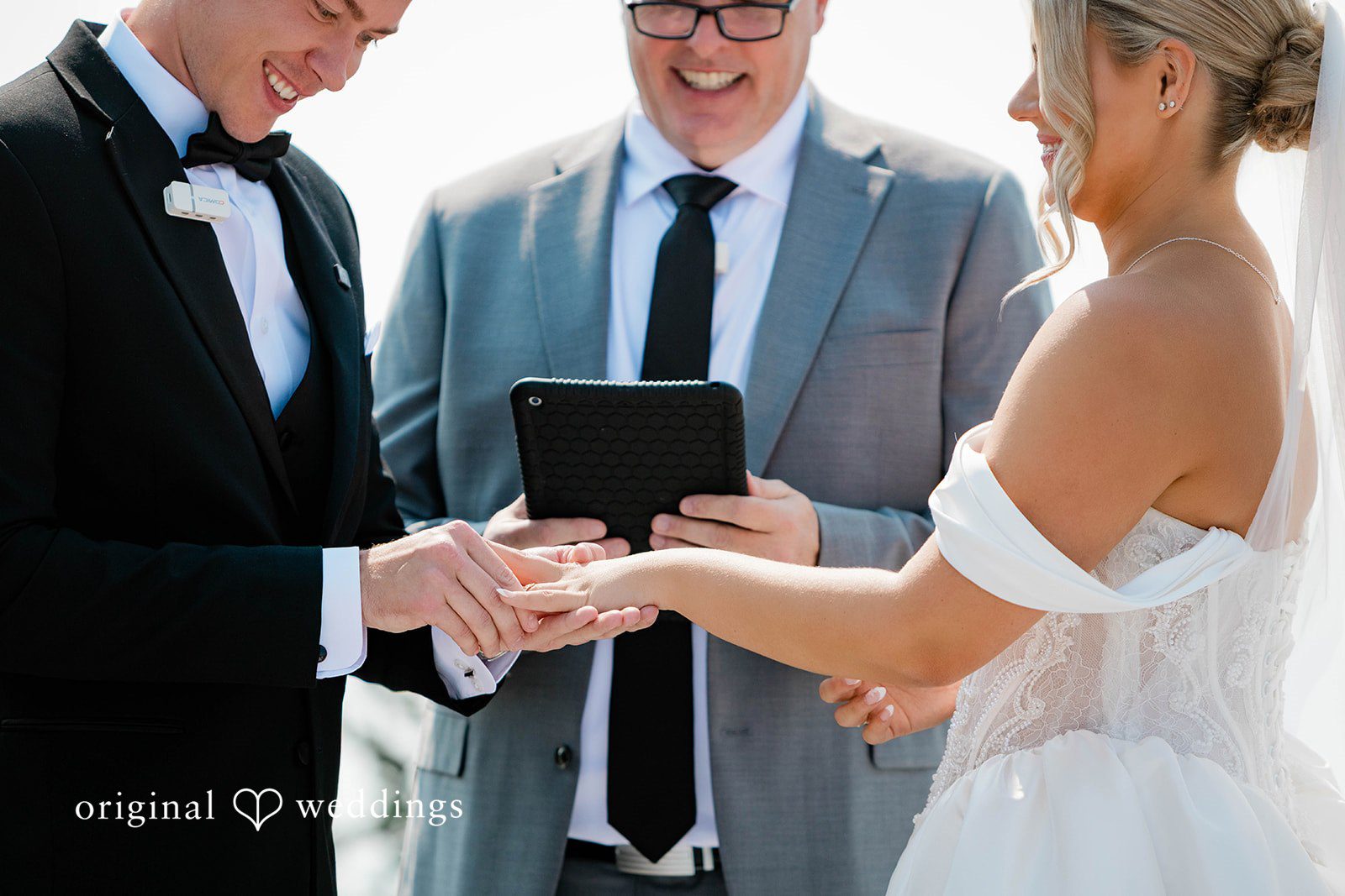 Bethany + Ryan A bride and groom look at each other while the officiant holds a script box.