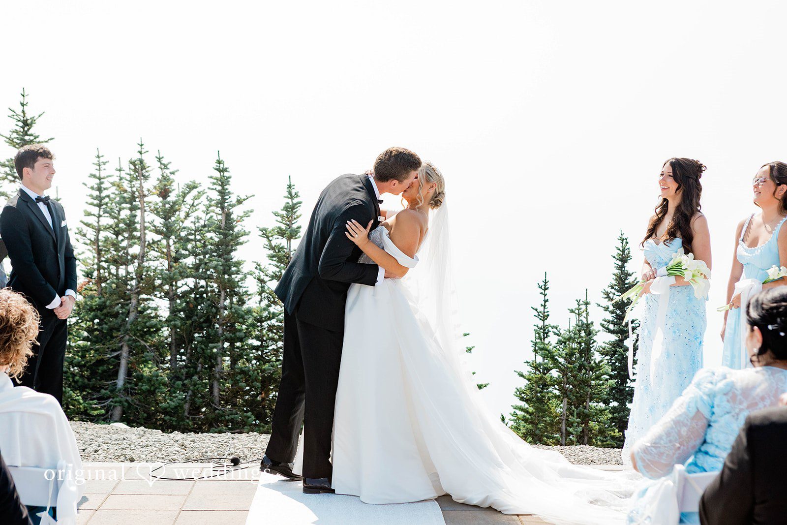 Bethany + Ryan A bride and groom share a kiss at the altar with mountains in the background.
