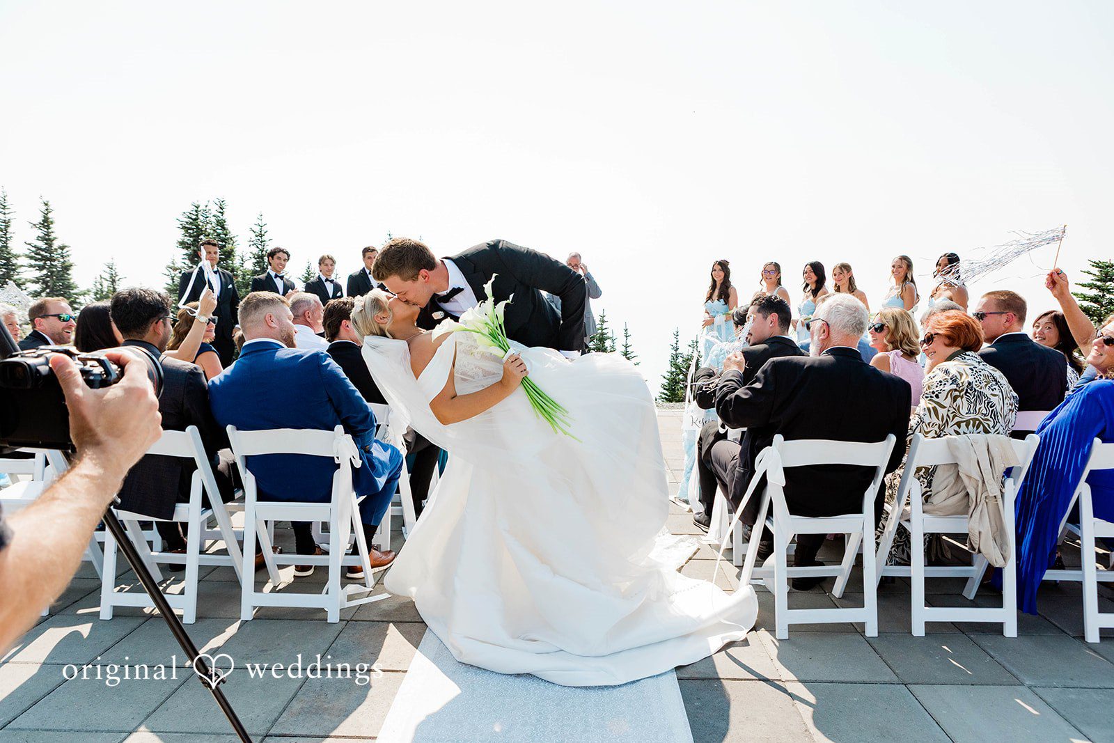 Bethany + Ryan A bride and groom walk down an aisle with seated guests watching.
