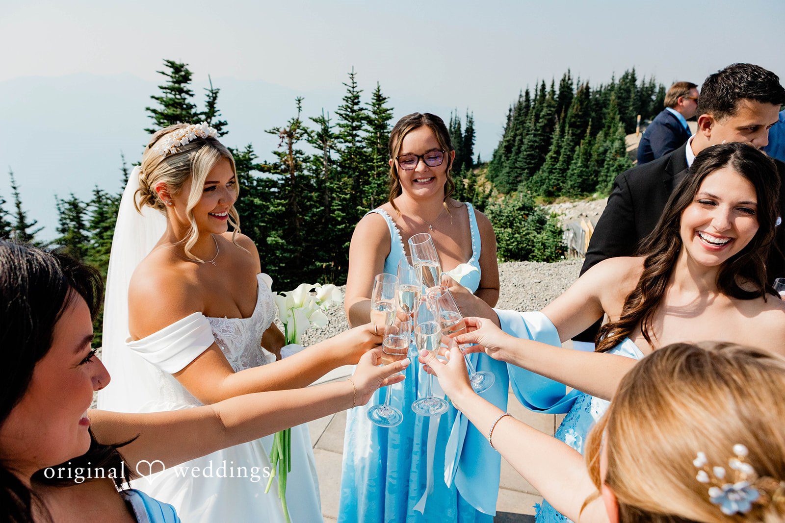 Bethany + Ryan A bride clinks glasses with her bridesmaids dressed in matching blue gowns.