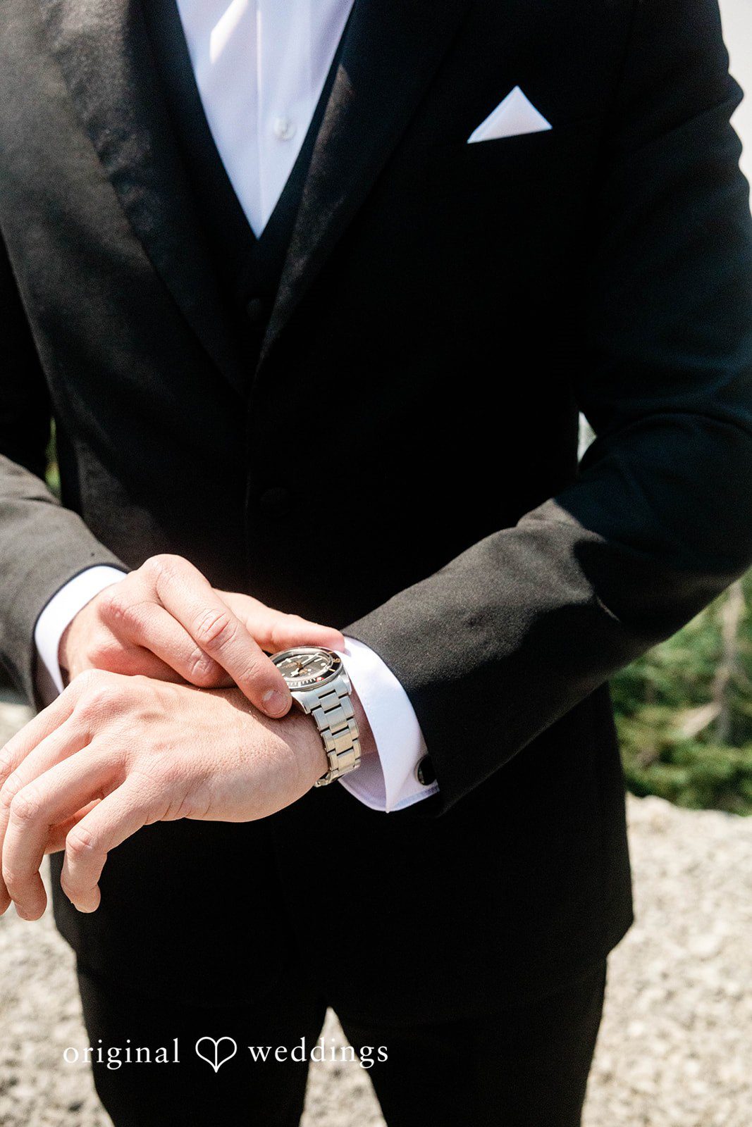Bethany + Ryan A close-up shot of a groom in a black tuxedo adjusting his watch cufflink.