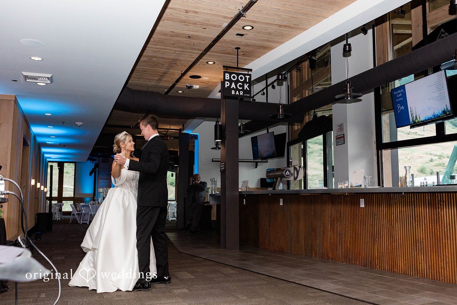 Bethany + Ryan A bride and groom dance together near a bar area inside a wedding venue.