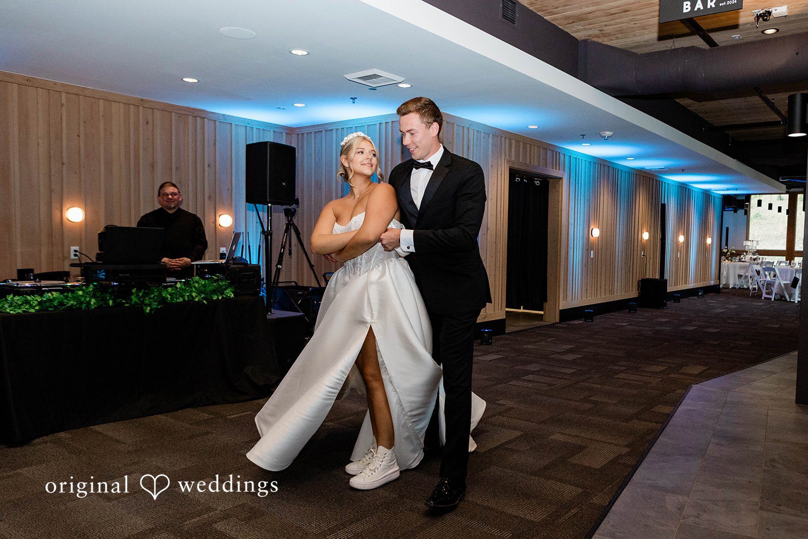 Bethany + Ryan A bride and groom stand together on an open dance floor with blue accent lighting.