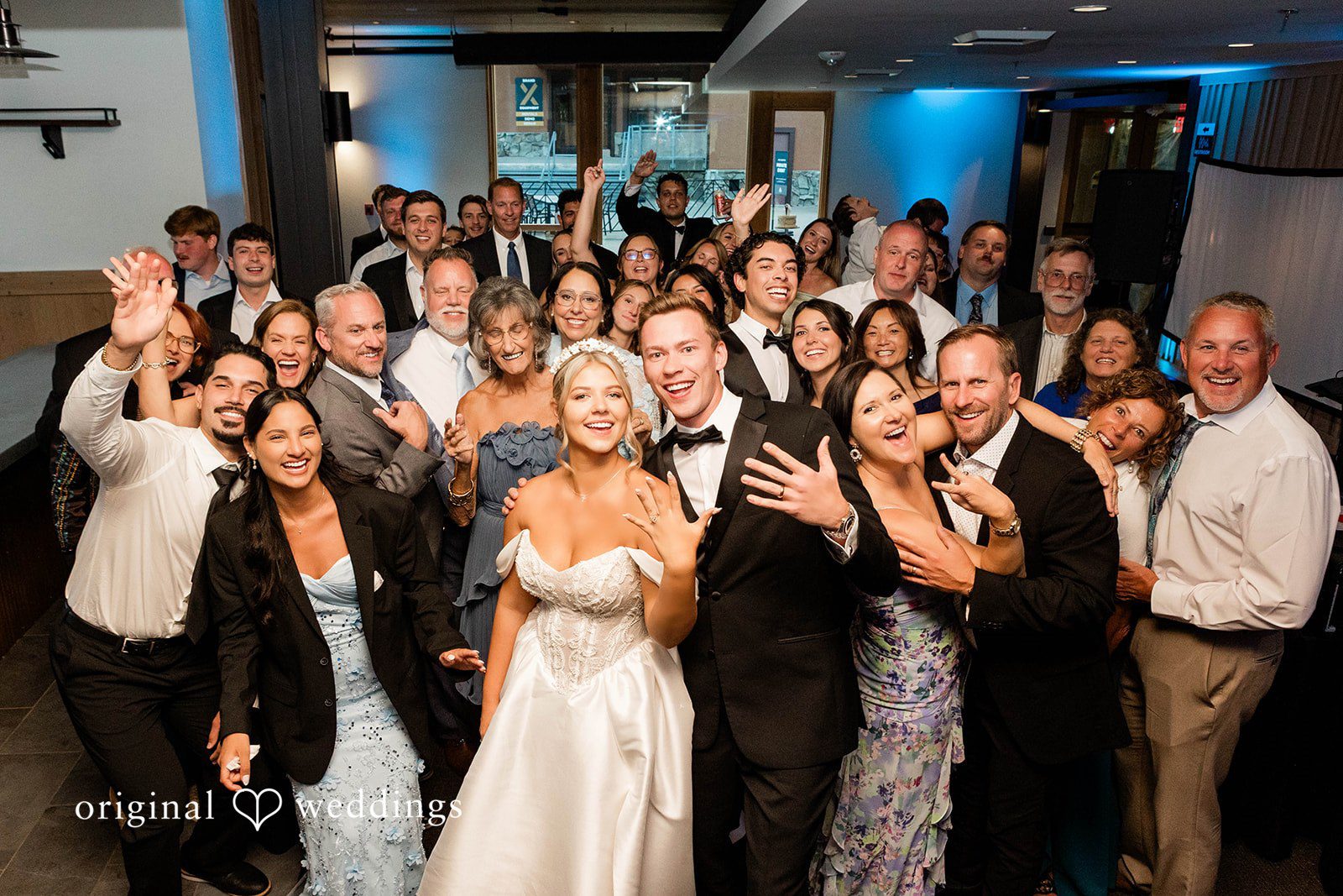 Bethany + Ryan A large group of wedding guests crowd onto the dance floor celebrating together.
