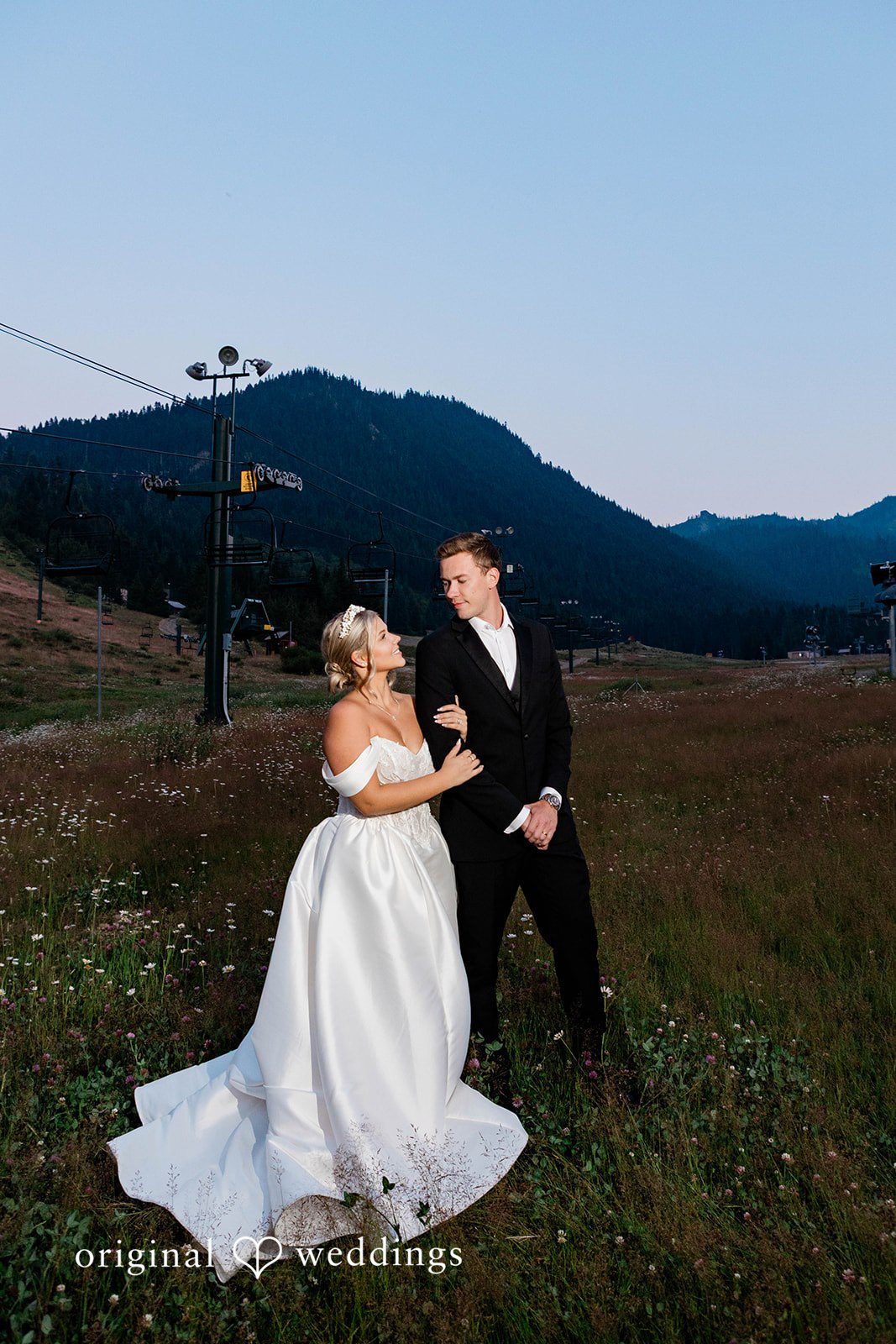 Bethany + Ryan A bride and groom stand together on a grassy hill during a twilight photo session.