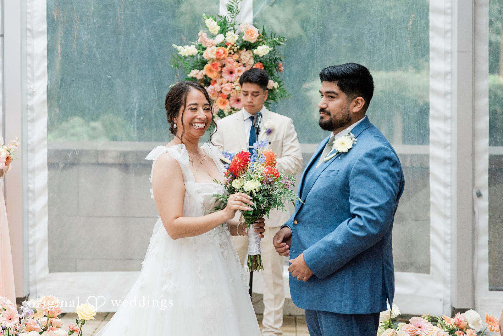 Couple standing under the floral arch at the ceremony at Curtis Arboretum