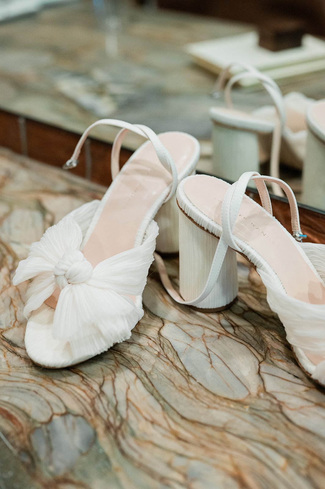 Bride's white wedding shoes on a marble surface