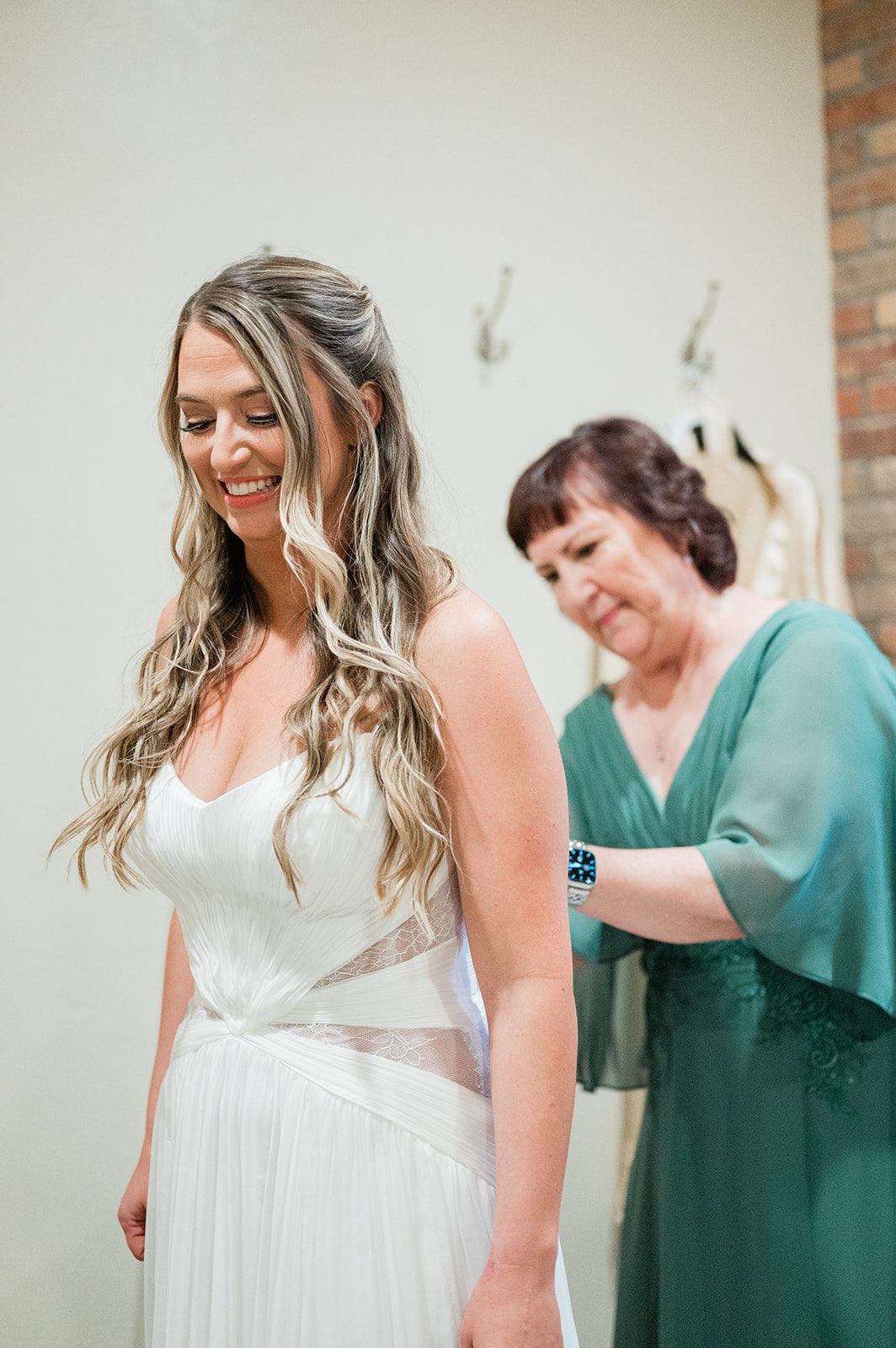 Mother of the bride helping the bride into her wedding dress