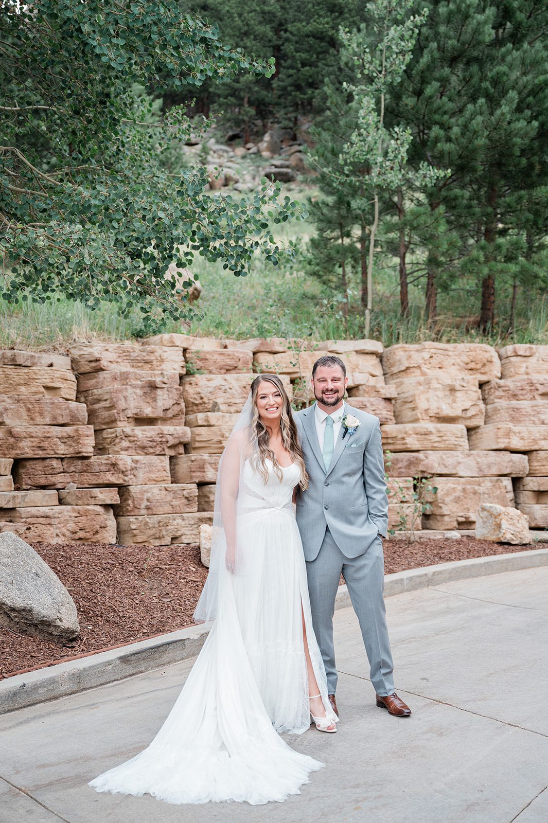 Bride and groom smiling in front of a rock wall