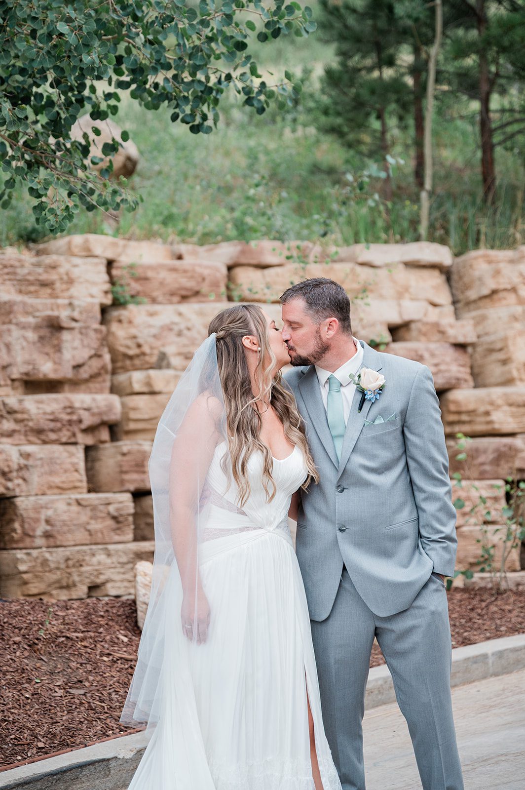 Bride and groom sharing a kiss by the stone wall