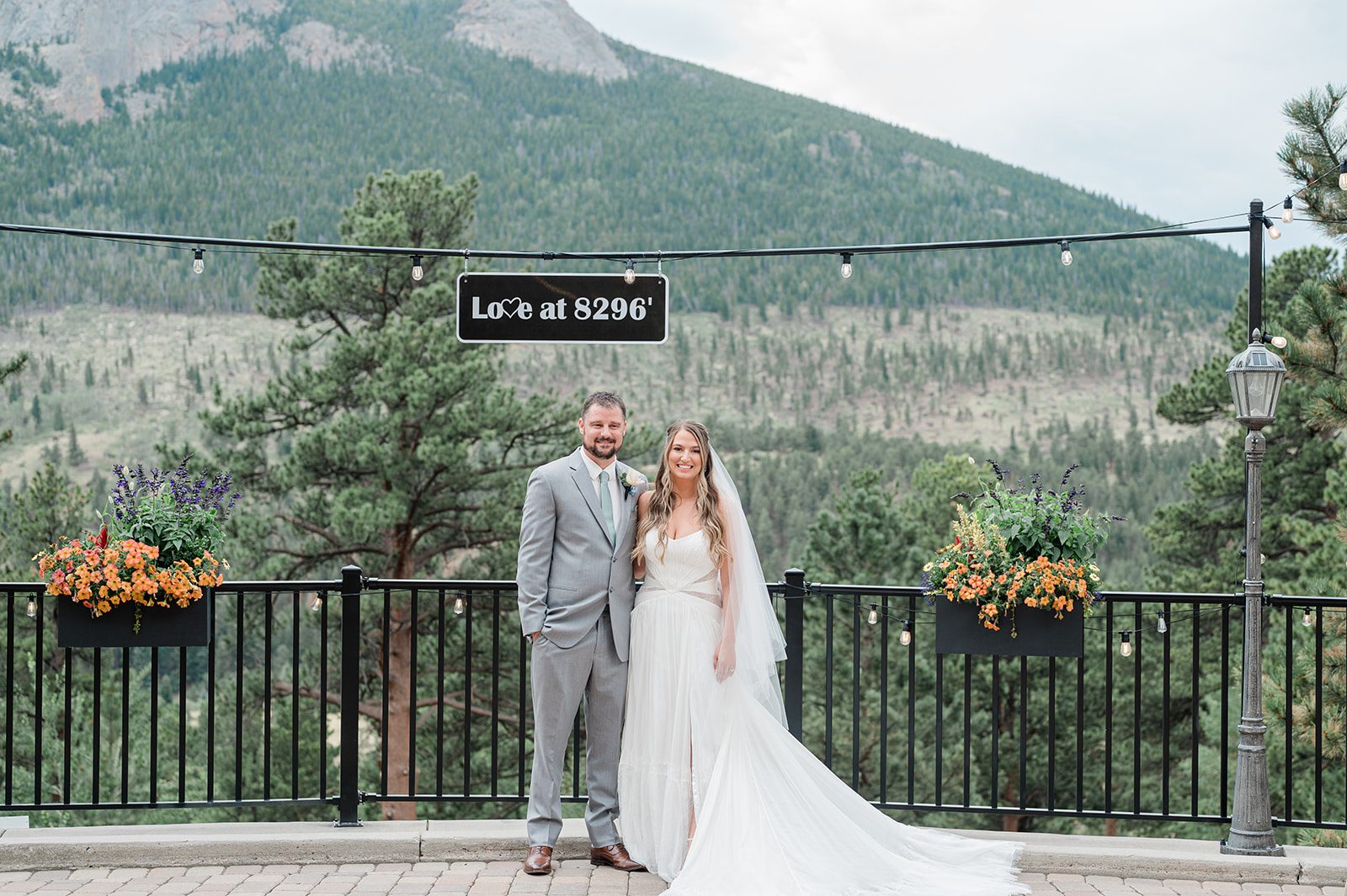 Bride and groom smiling at the railing with mountain views, captured by Denver wedding photographers from Original Weddings at Della Terra Mountain Chateau