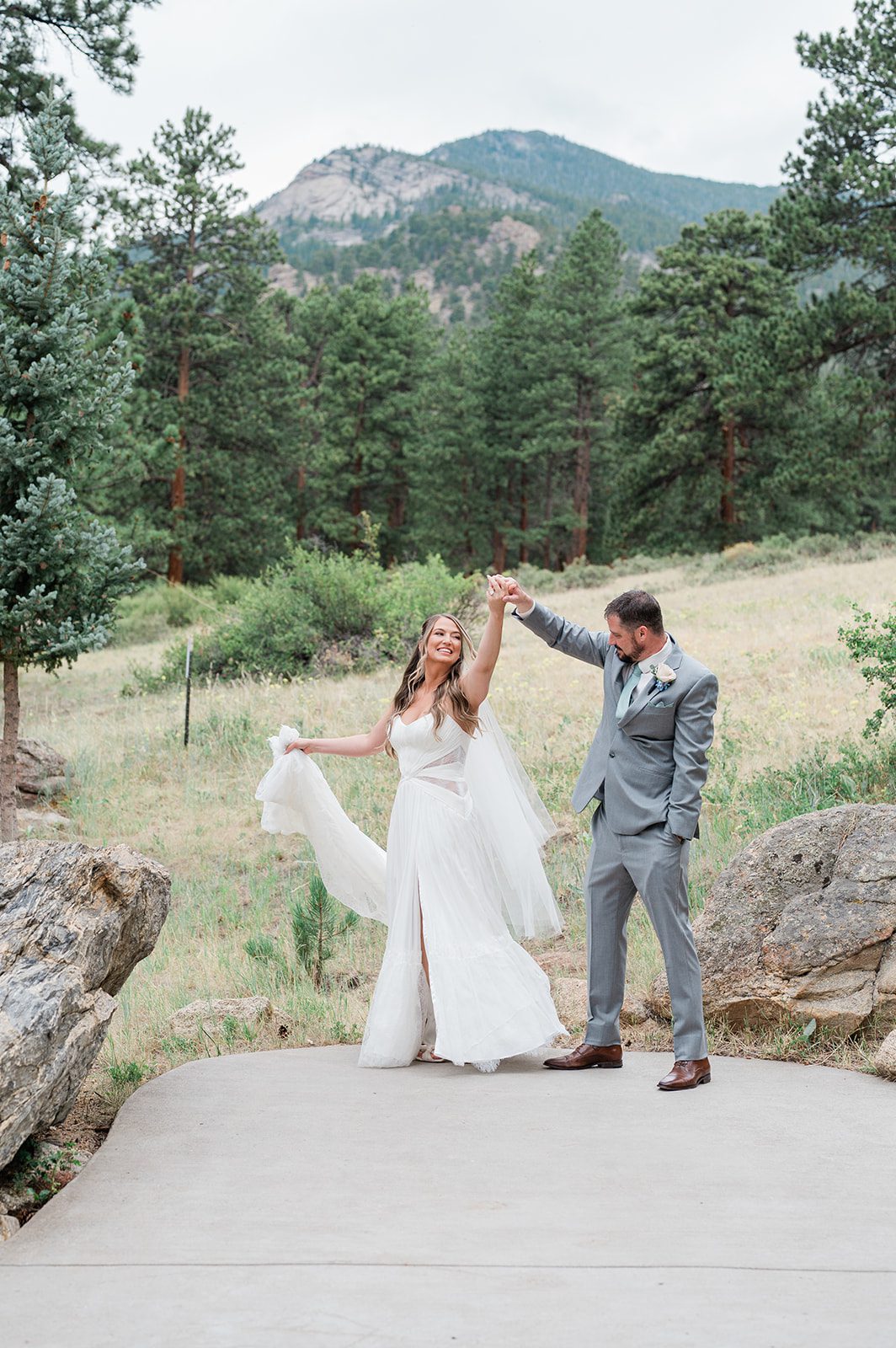 Groom twirling the bride in a mountain meadow
