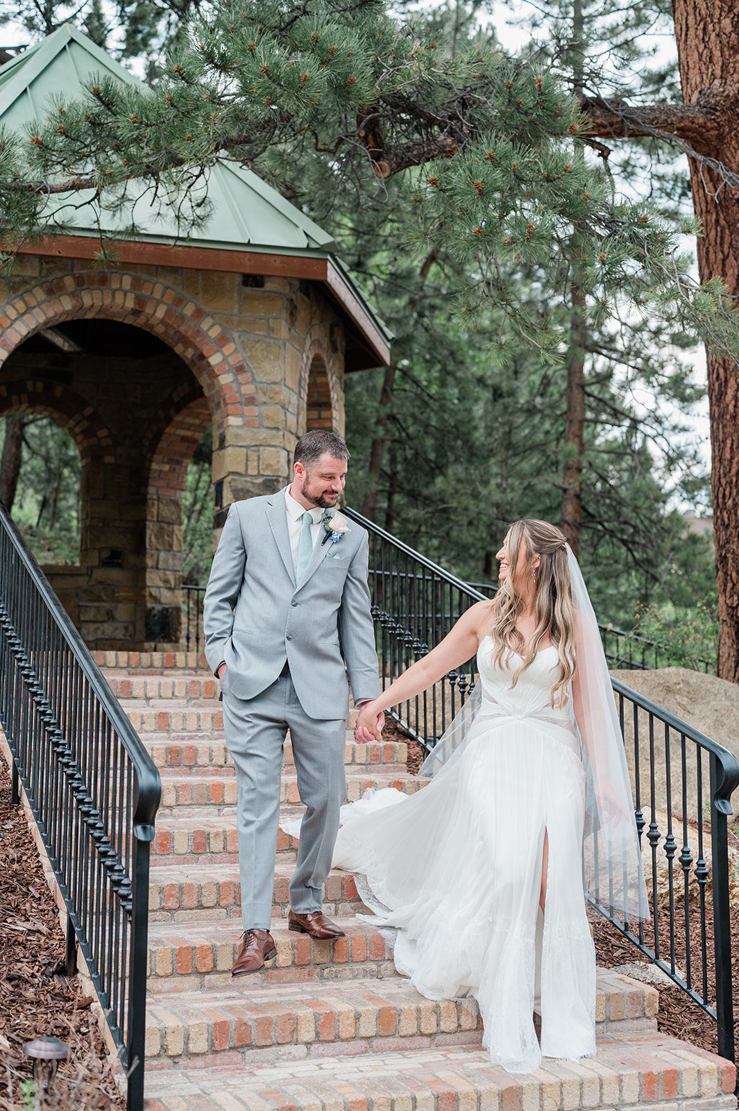 Bride and groom on the gazebo stairs among the pines