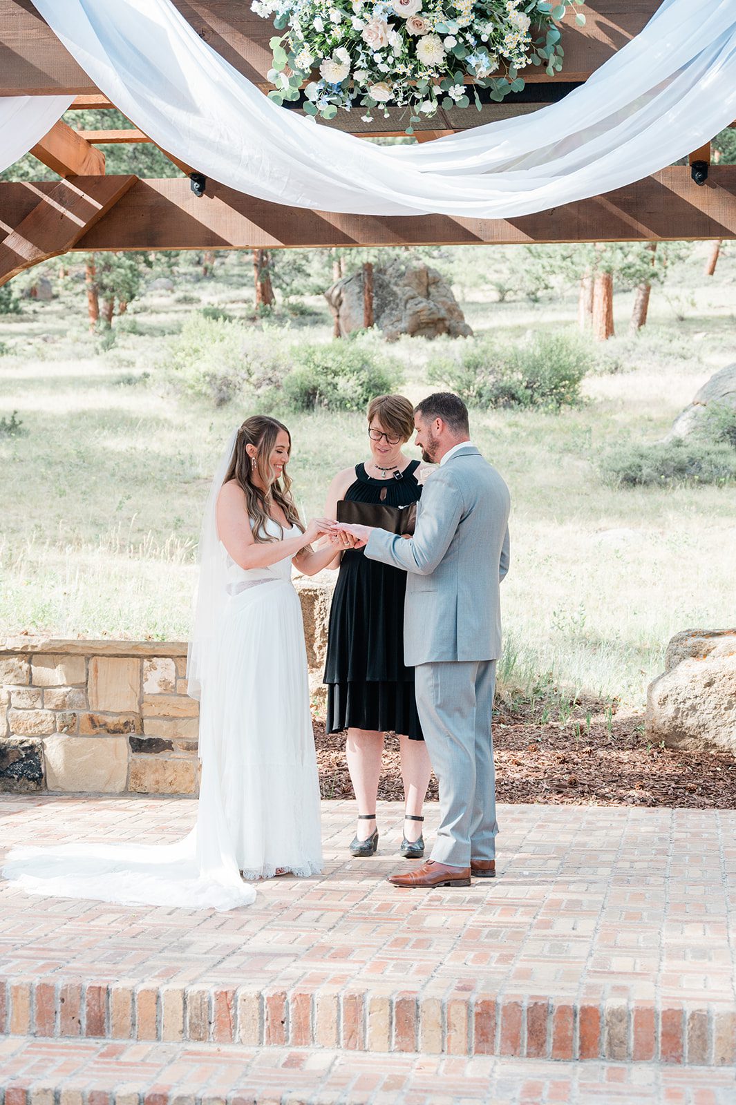 Couple exchanging vows with the officiant under the draped arbor