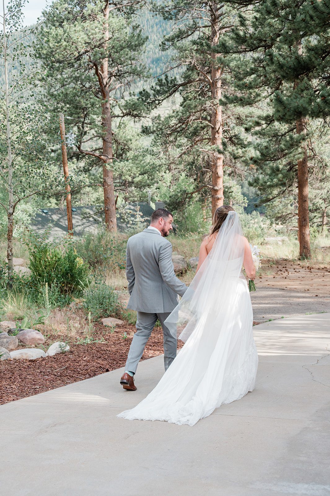 Newlyweds walking together among tall pines